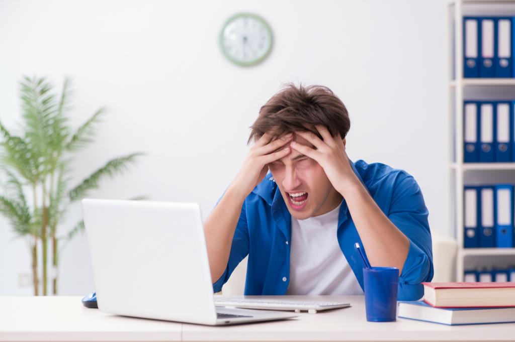 Young man looking tired and stressed at his desk