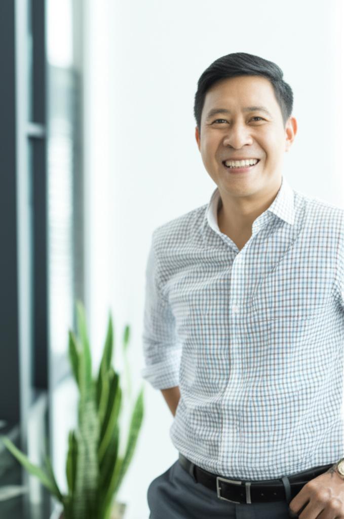 ai prompt: A confident middle-aged Asian man smiling, looking energetic, in a modern setting, representing improved vitality and confidence